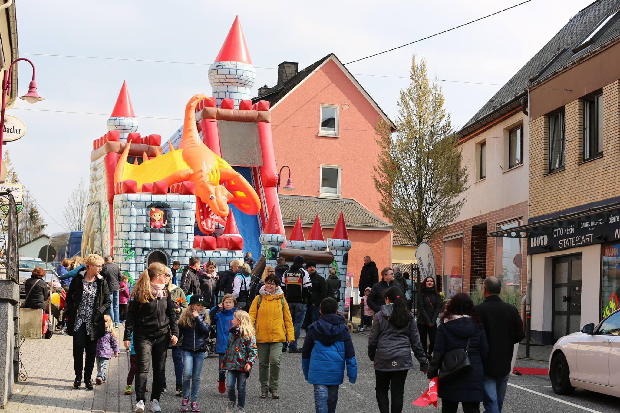 Buntes Straßenfest mit einem Drachen-Inflatable auf einer verkaufsoffenen Sonntagsveranstaltung in Westerburg, wo Familien und Besucher lokale Geschäfte erkunden.