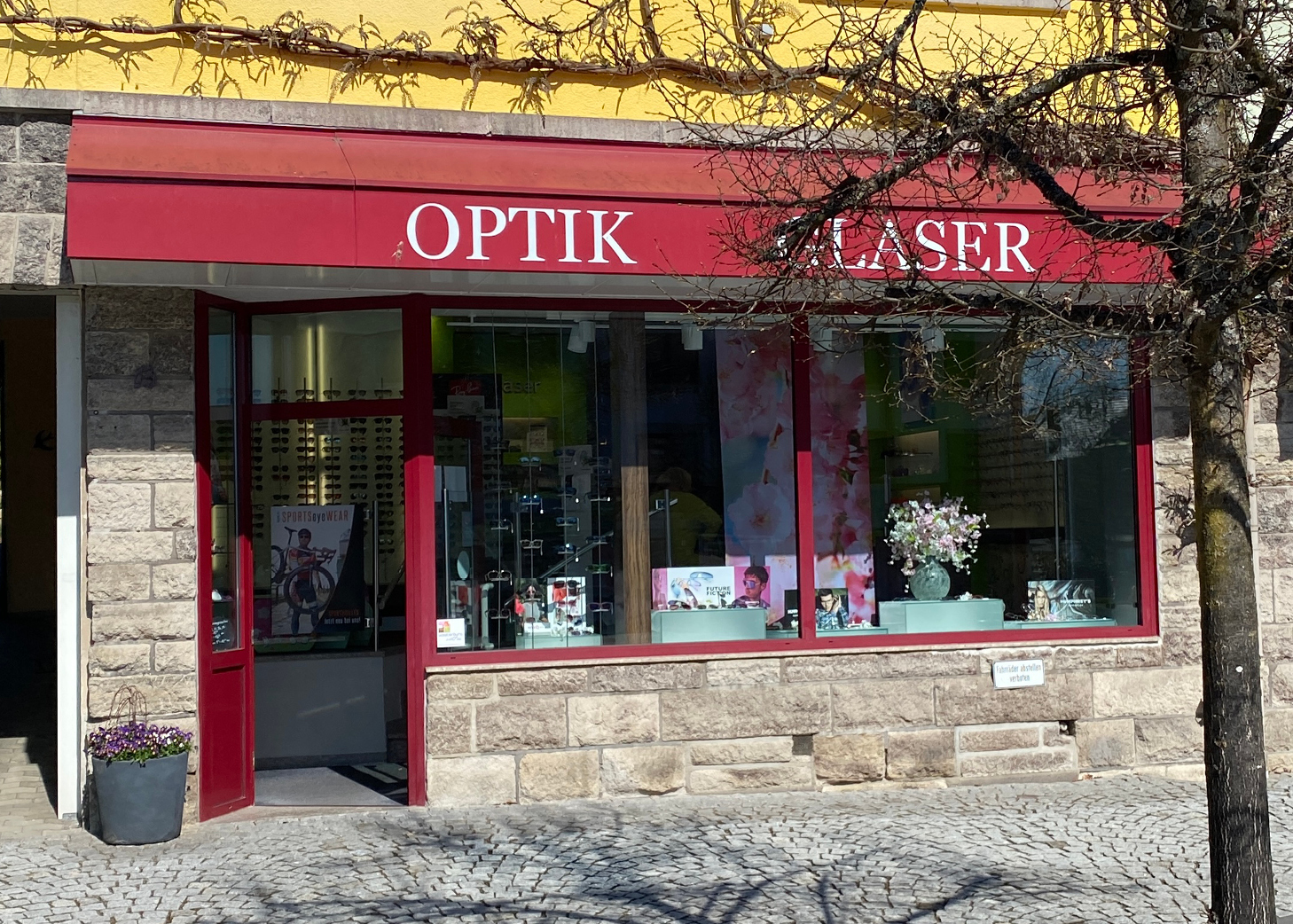 Fassade eines Optikgeschäfts mit roter Markise, der Aufschrift 