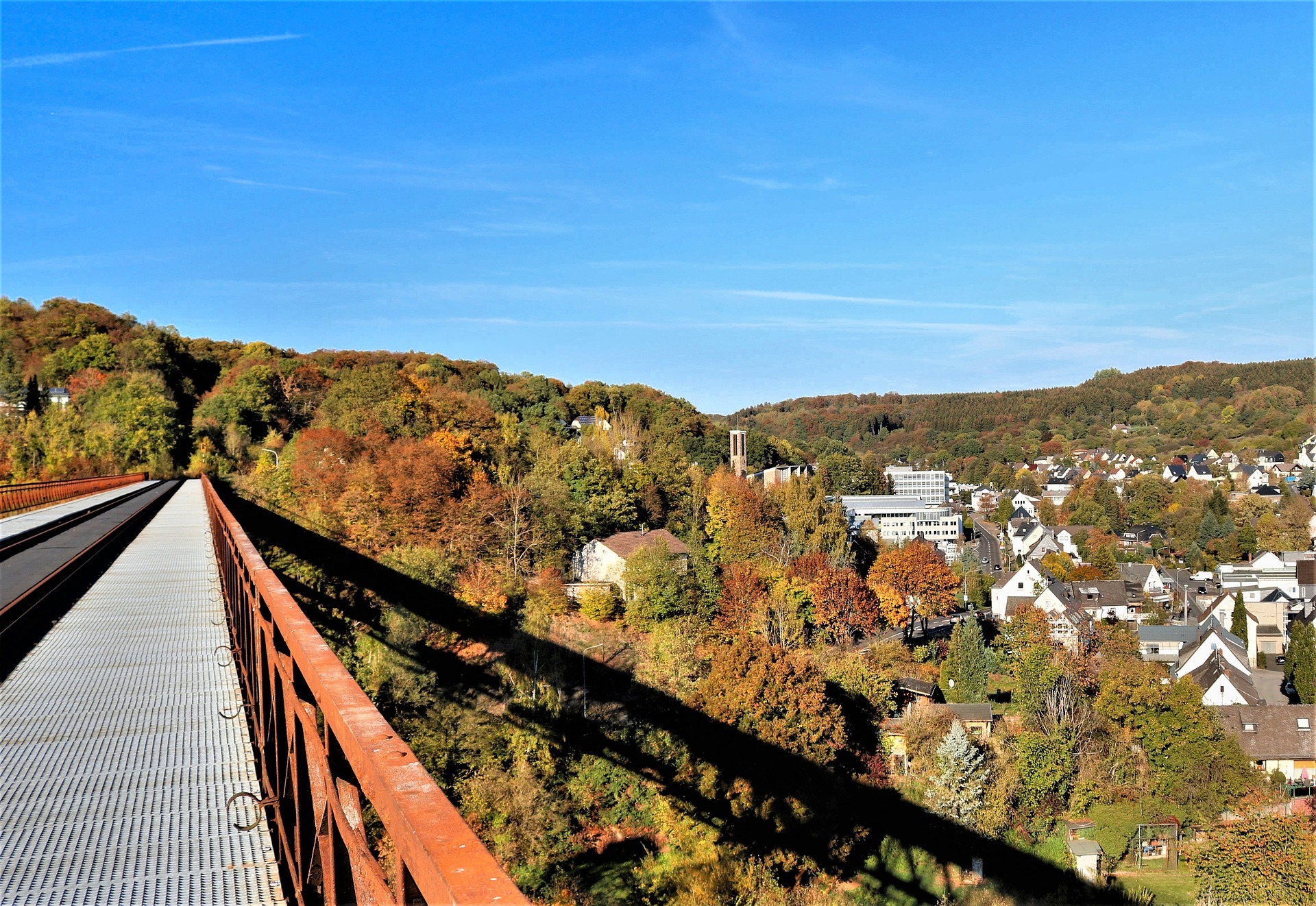 Blick von einer Brücke auf die Stadt Westerburg mit herbstlichem Wald und gemischter Bebauung, die die lebendige lokale Wirtschaft repräsentiert, die der Gewerbeverein Westerburg stärkt.