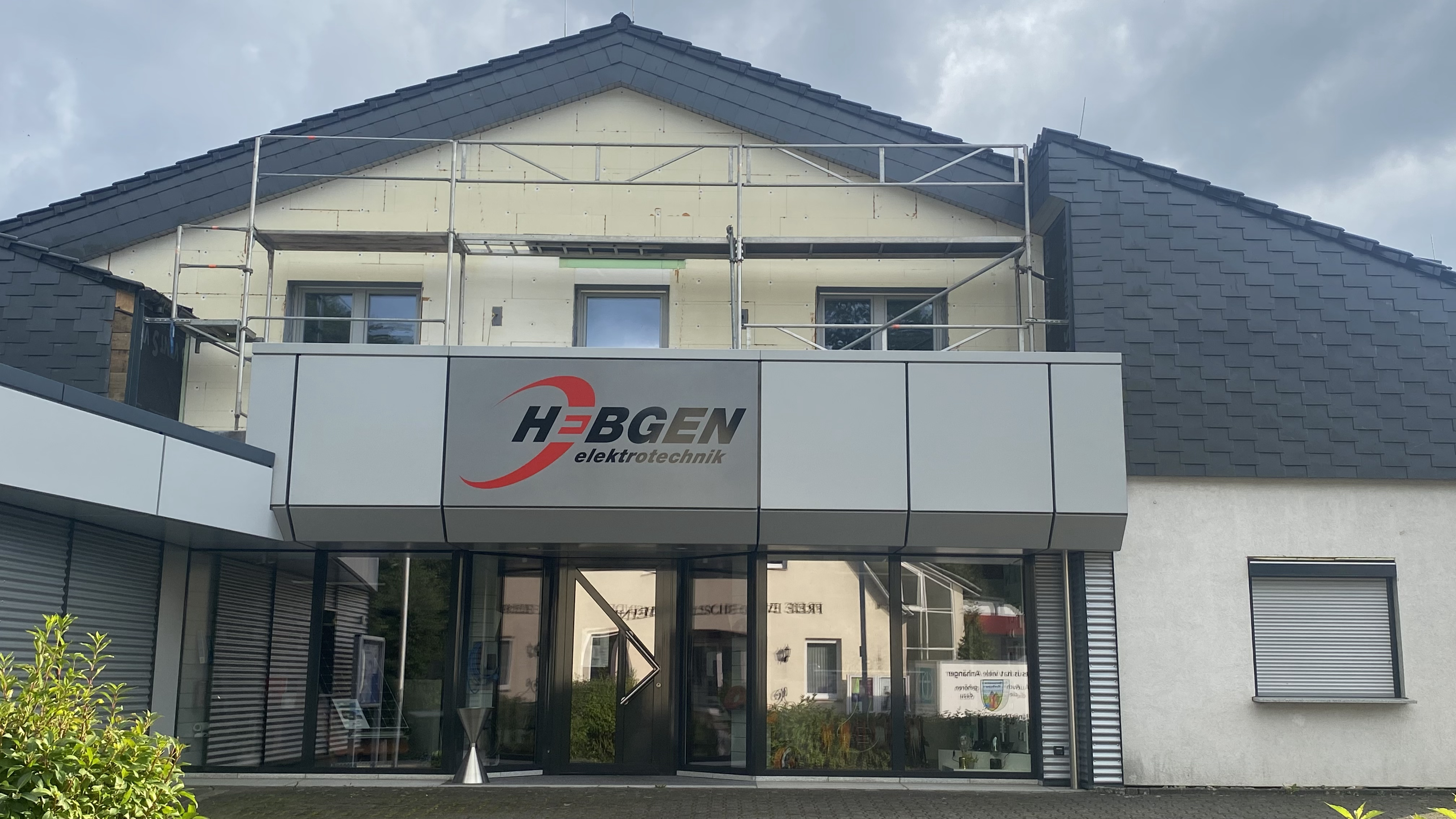 Frontansicht des Hebgen Elektrotechnik-Gebäudes mit moderner Fassade, Glasschiebetüren und Firmenlogo, Mitglied des Gewerbevereins Westerburger Land.